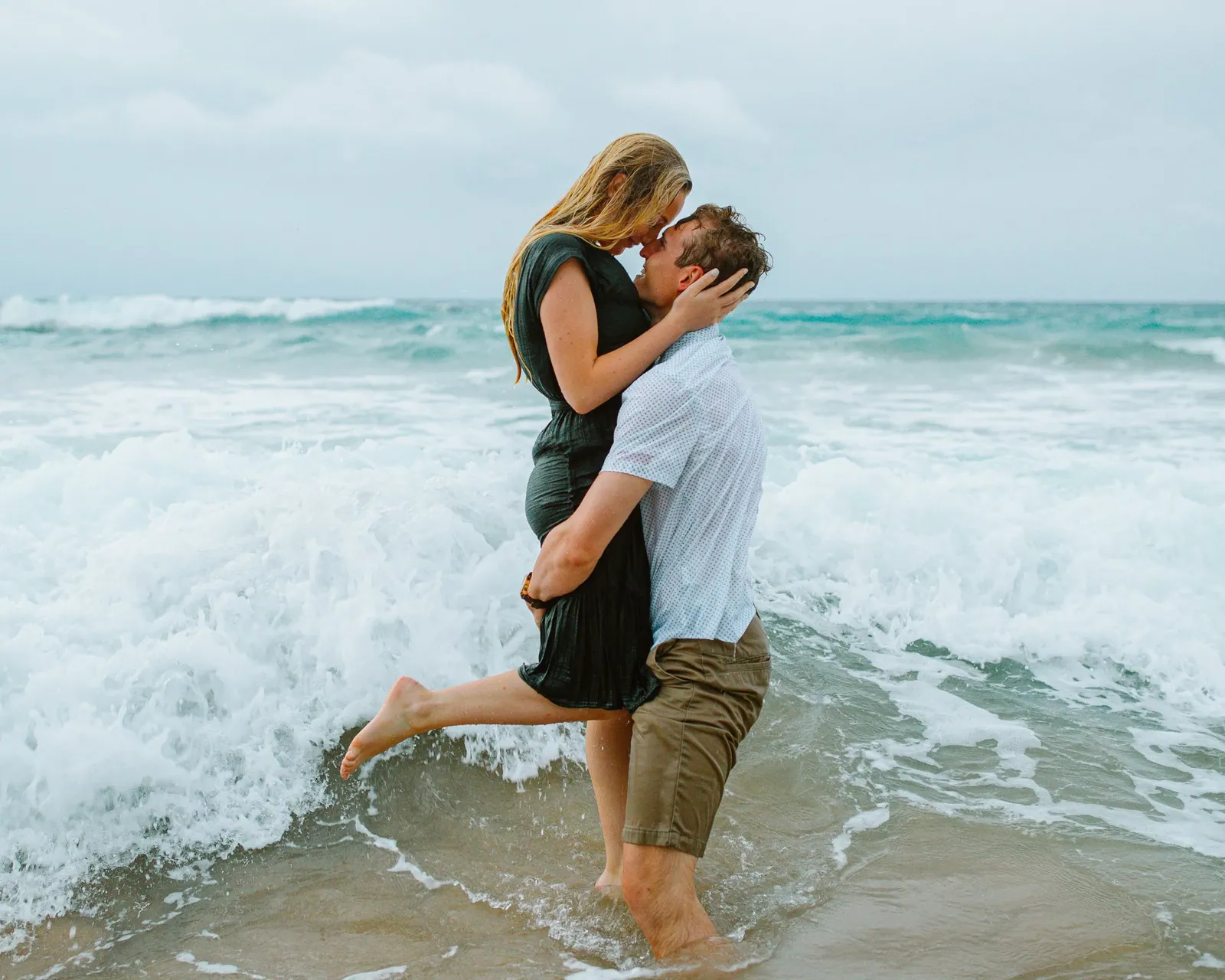Couple in the shallows, one kneeling, during a South Maui sunset session