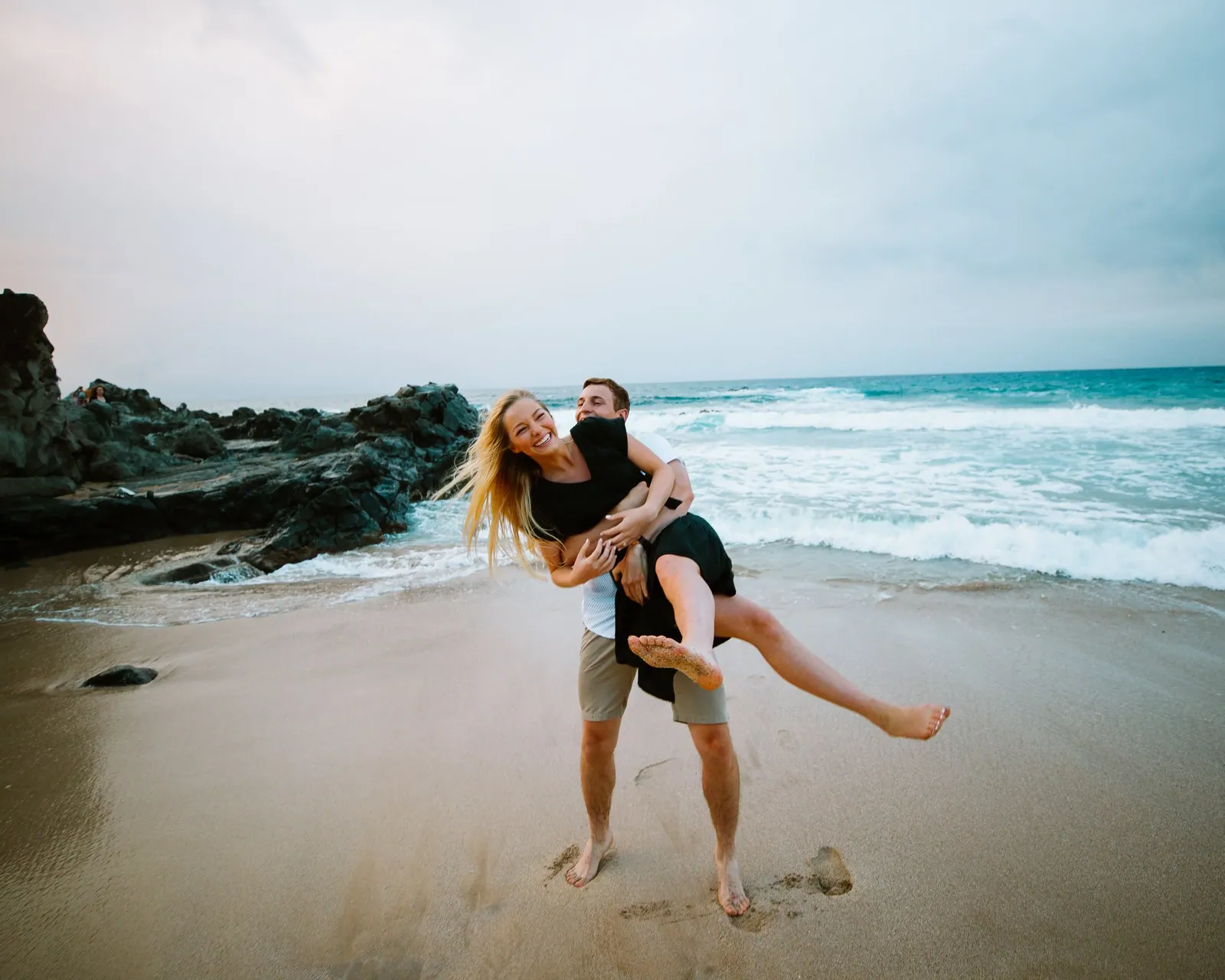 Couple playing in the shore break during a Maui beach session