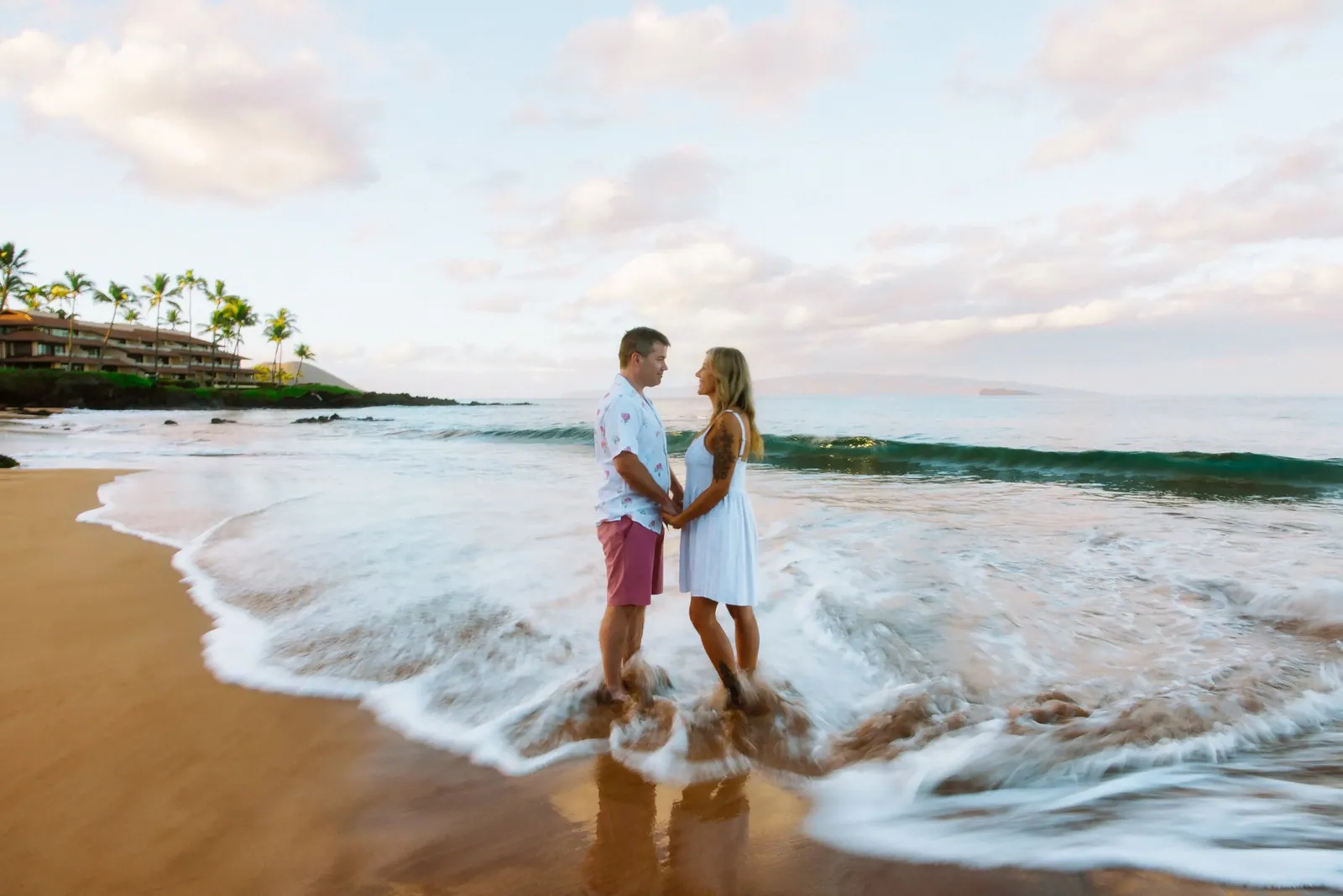 Couple embracing on the sand under a soft Maui sunset