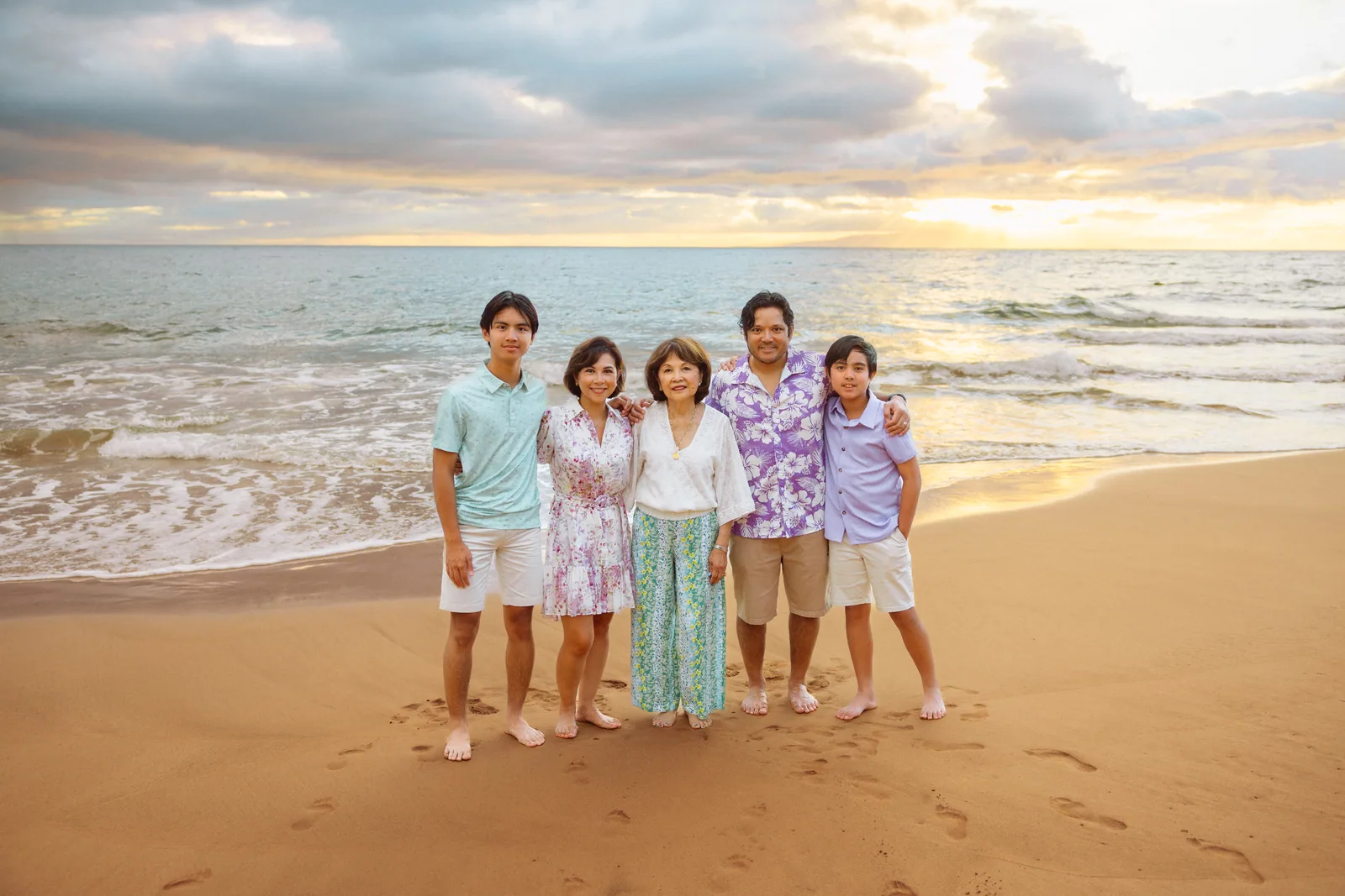 A family photographed together on the sand under a broad sunset
