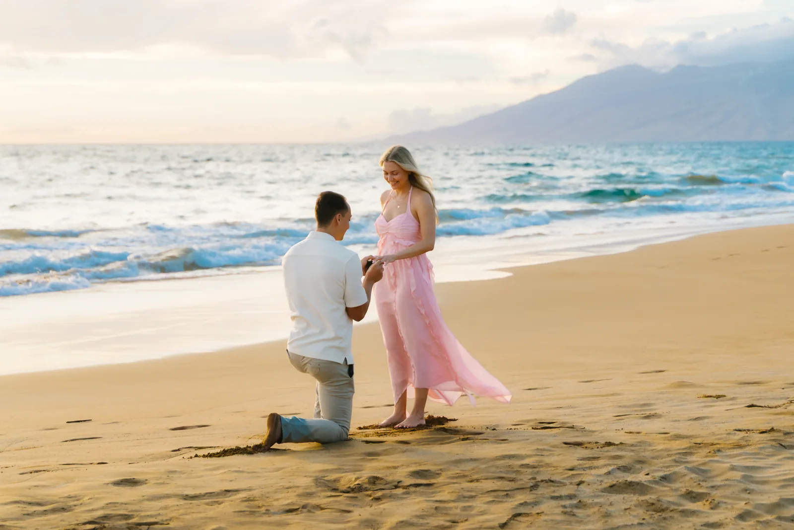 A proposal at the water's edge, photographed from down the beach
