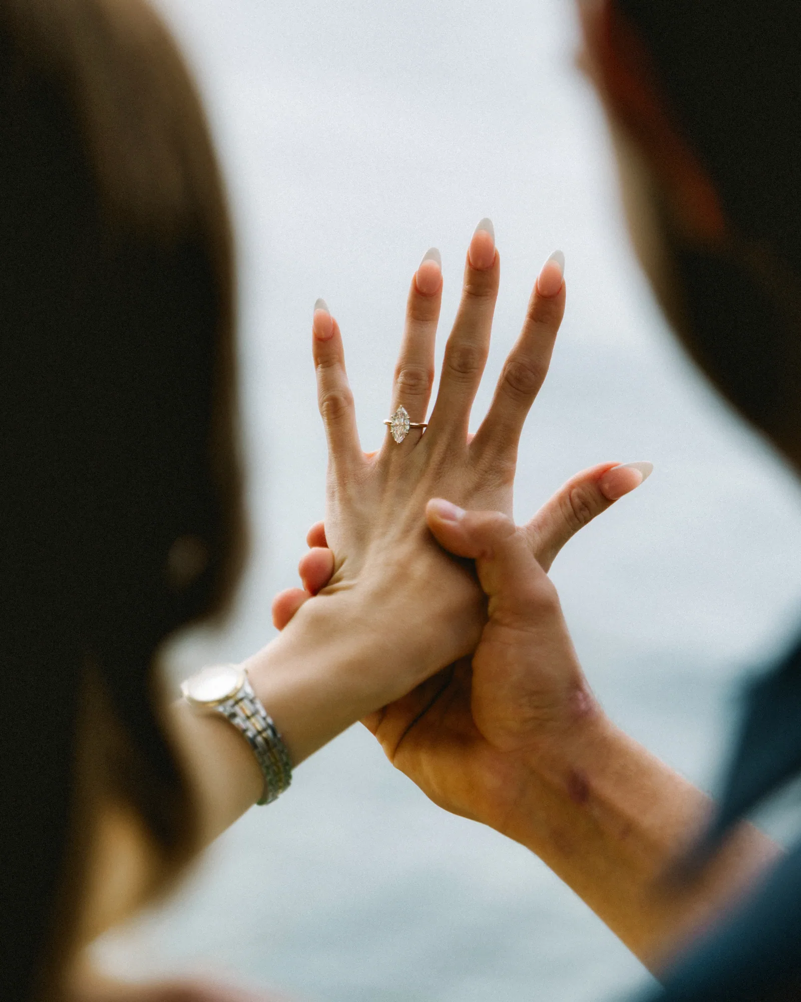 A close frame of the new ring on her hand, held up between them