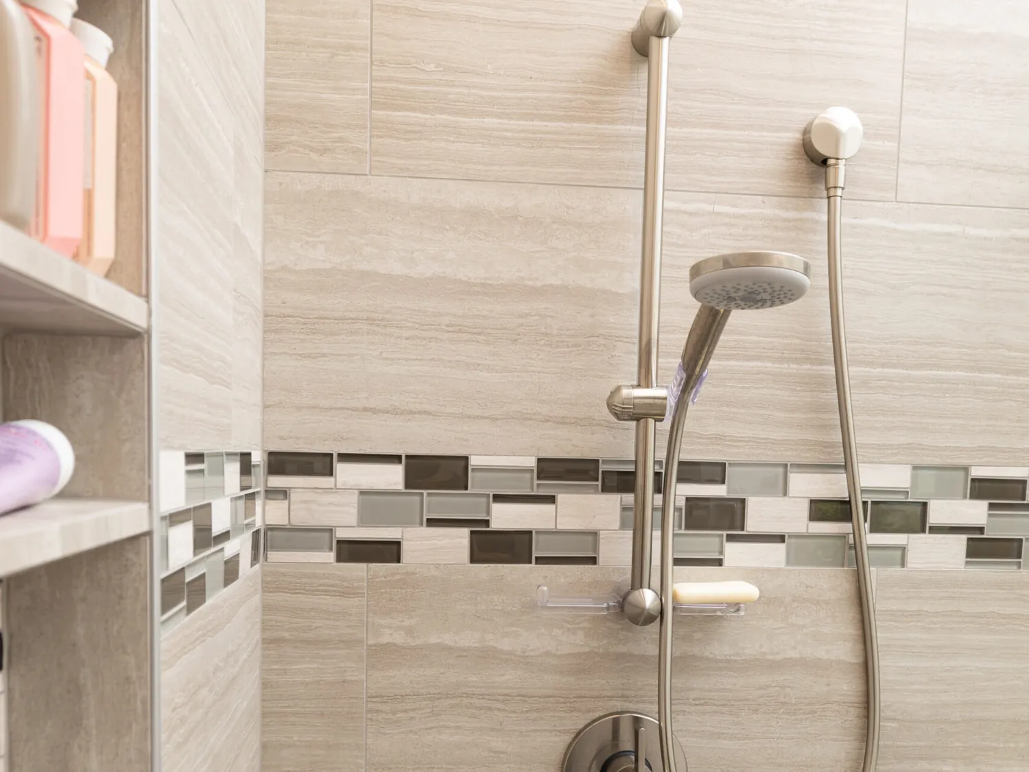 Bath designed by Kalluna Interior Design — A neutral tile shower with a horizontal mosaic band and a bench built in at the right height.
