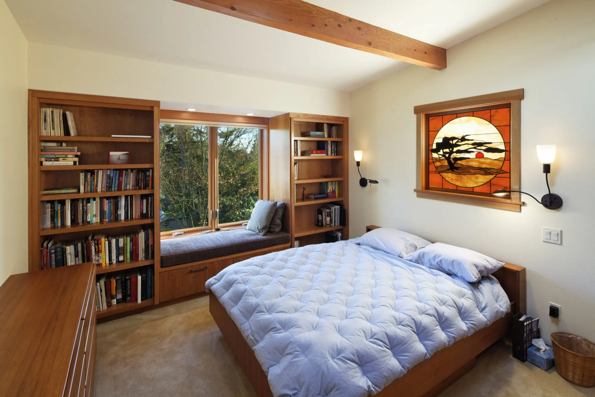 A bedroom with floor-to-ceiling built-in shelving flanking a window seat