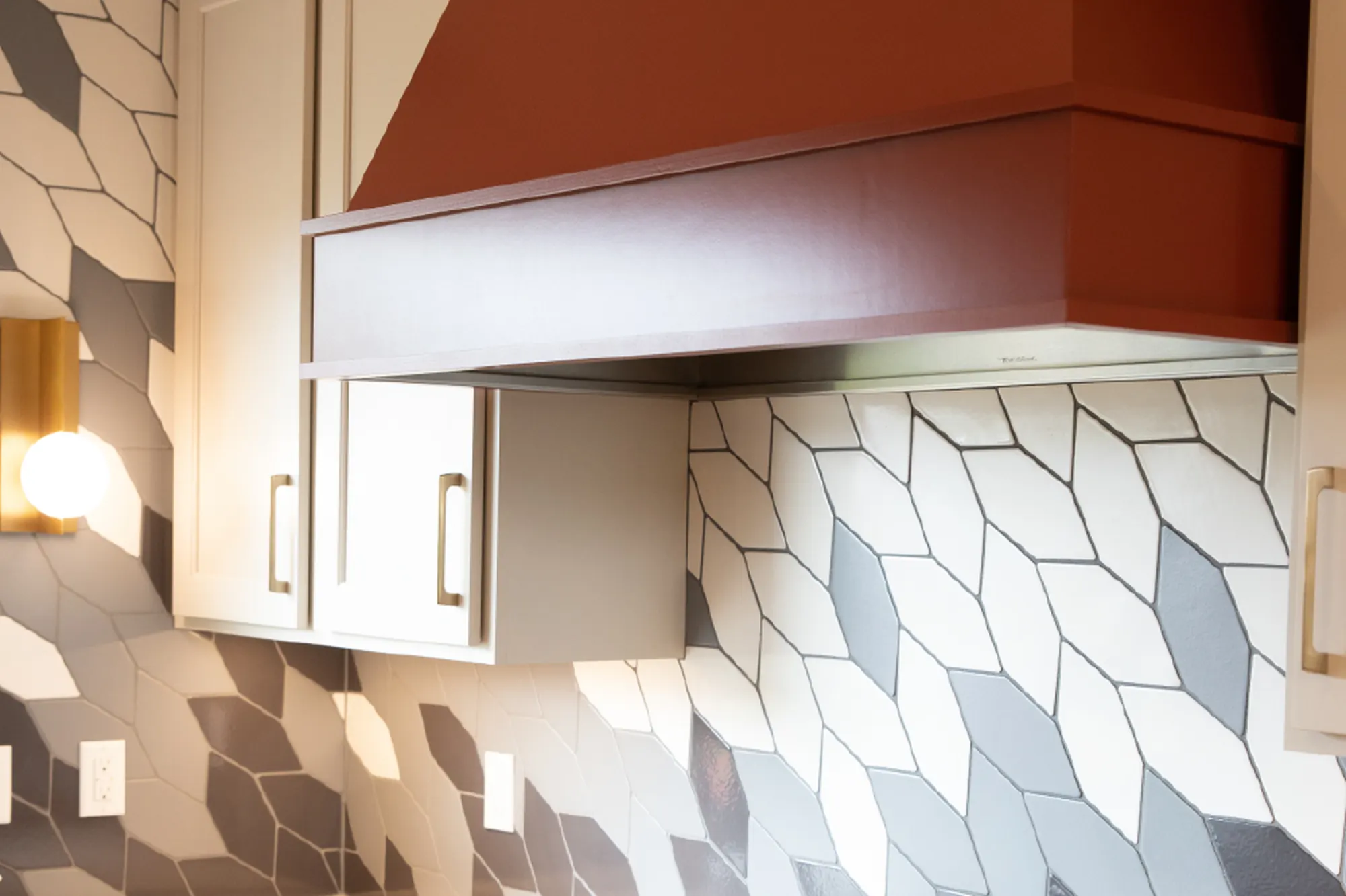 A painted kitchen hood above a patterned geometric tile backsplash
