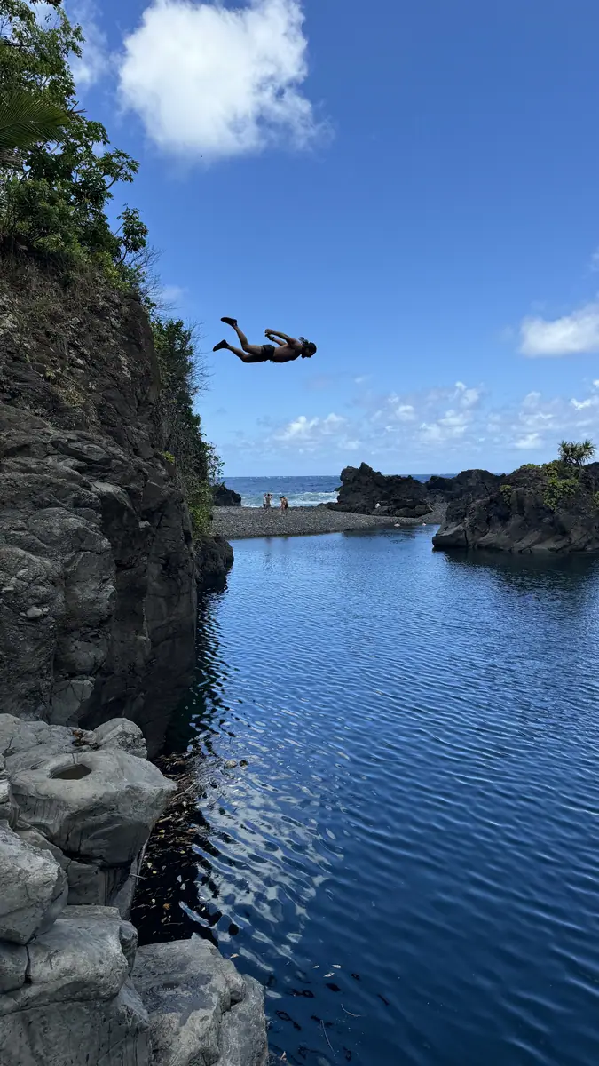 A deep blue freshwater pool ringed by lava rock, seen from above