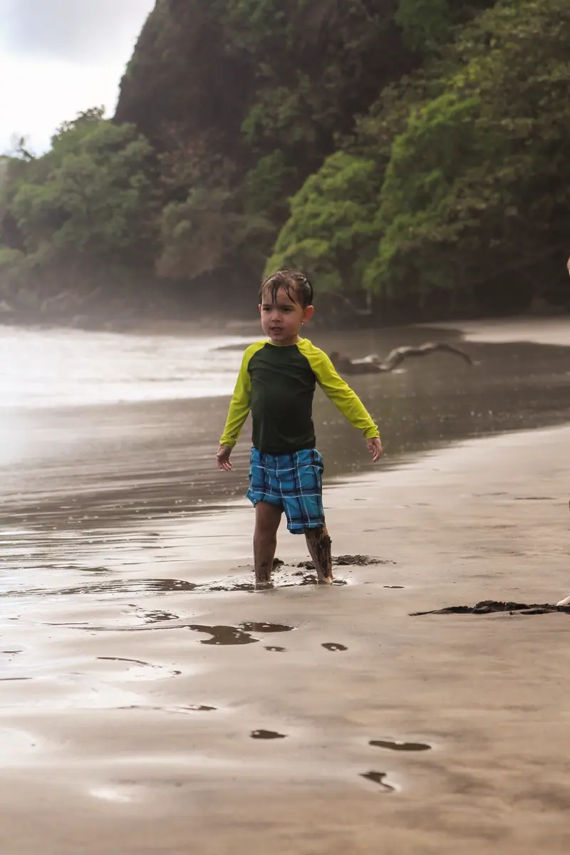 A small boy running along the water's edge