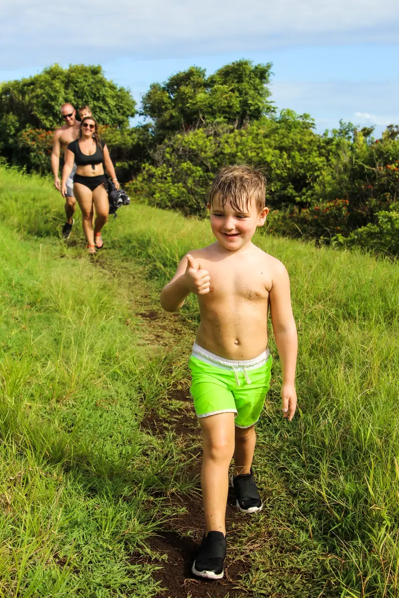 A boy running down a grassy trail toward the coast