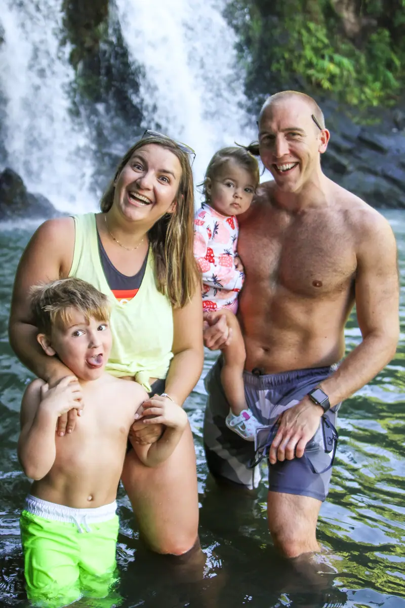 A family wading together at the base of a waterfall