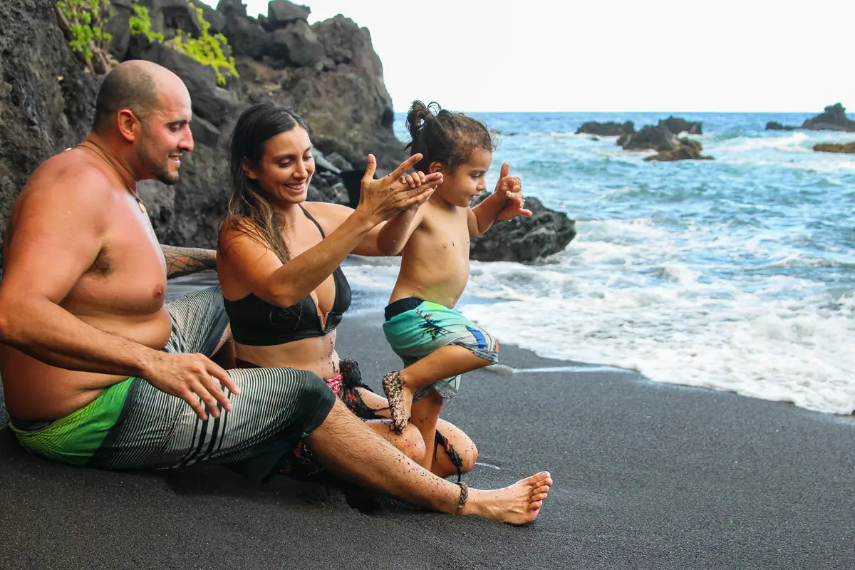 A family sitting together on black sand