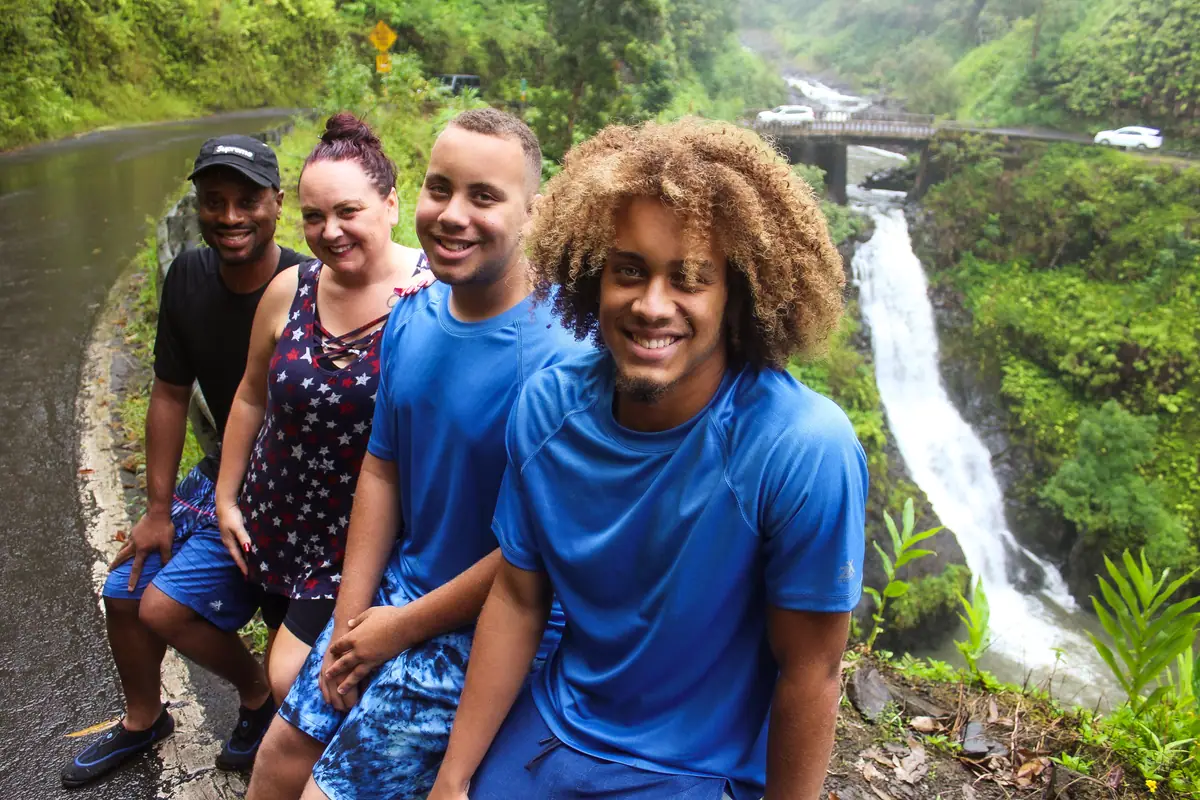 A group of guests posing at the base of a waterfall on the Road to Hana