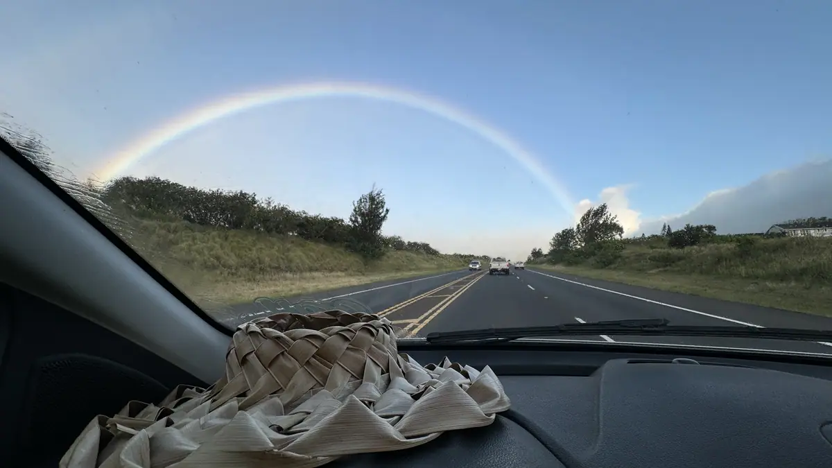 A rainbow over the highway seen through the windshield